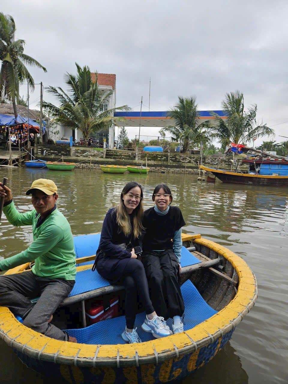 Two guests steered through the coconut palms by a basket boat rower in a green shirt