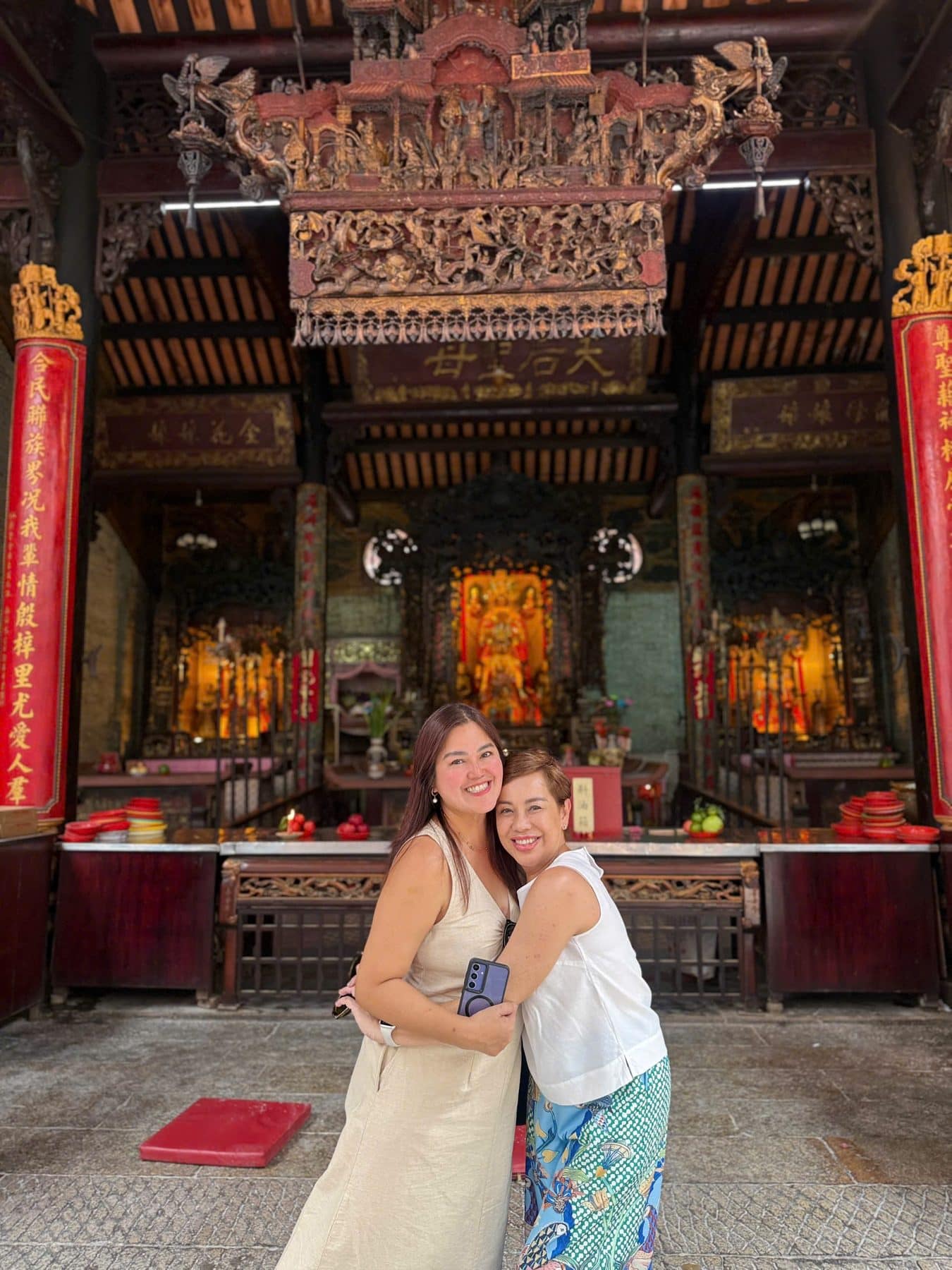 Two guests inside the carved timber hall of a Cholon temple