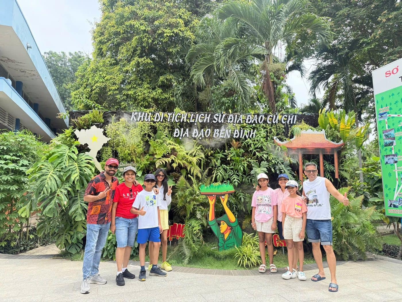 A family at the planted sign for the Ben Dinh tunnels at the Cu Chi historic site