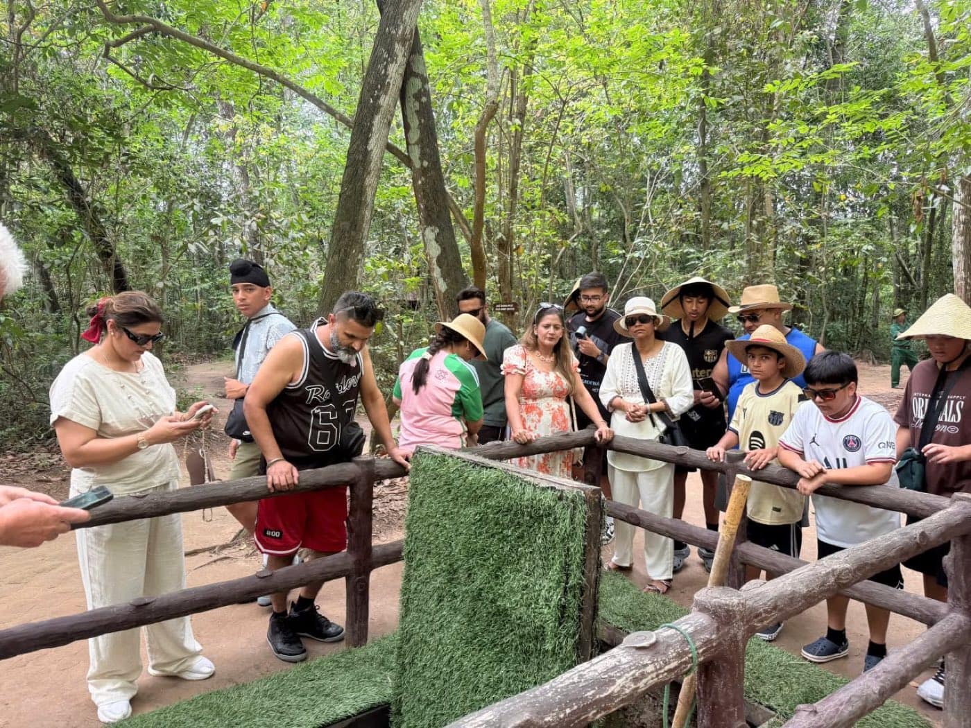 The grass-covered hatch cover lifted clear of its hole while the group watches from the rail