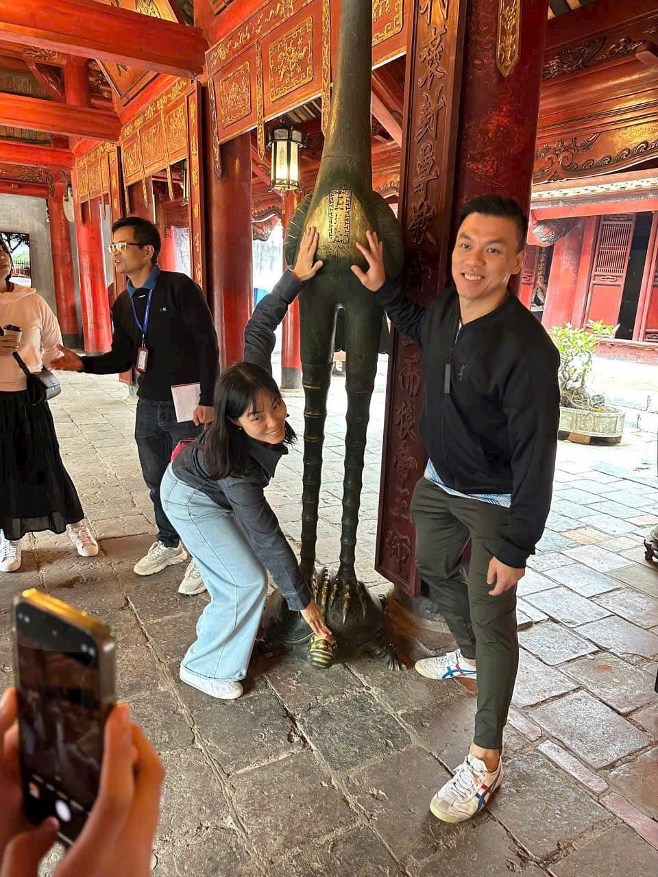 Two travellers in the red lacquer interior of a Hanoi temple