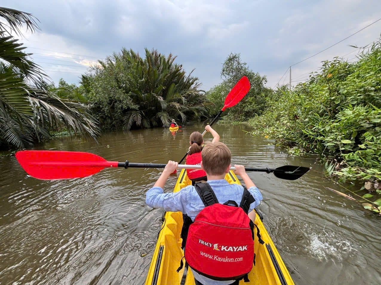 Paddling a tandem kayak down a green Mekong canal