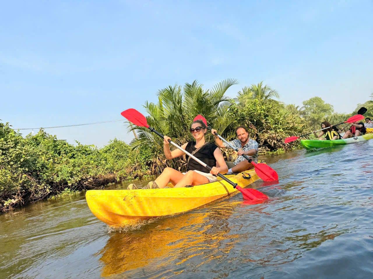 Two guests paddling a yellow kayak along the canal