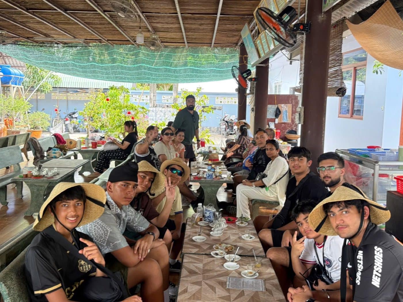 The group at the tasting tables in conical hats, cups and saucers in front of them