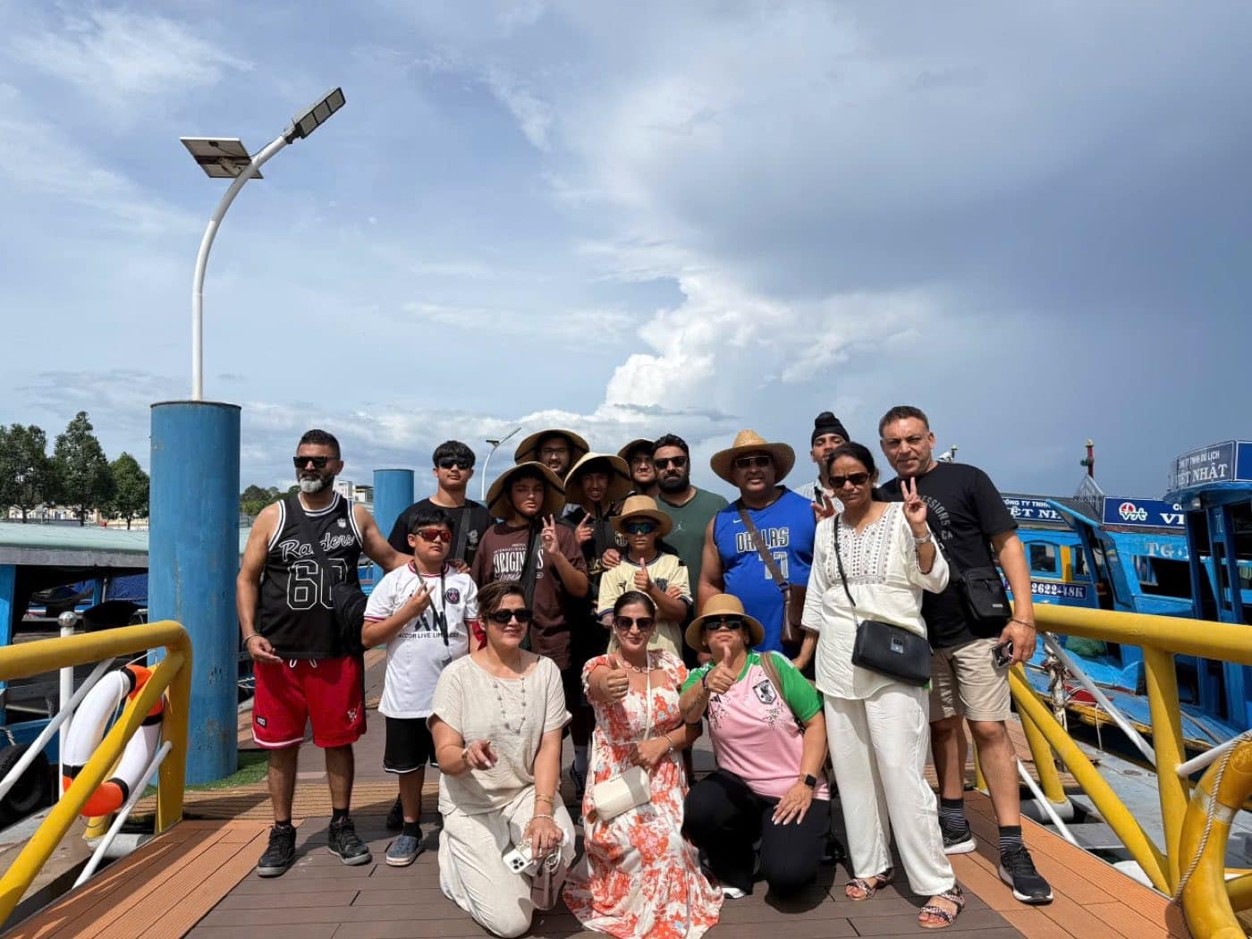 The group on the wharf before boarding, the blue river boats moored behind