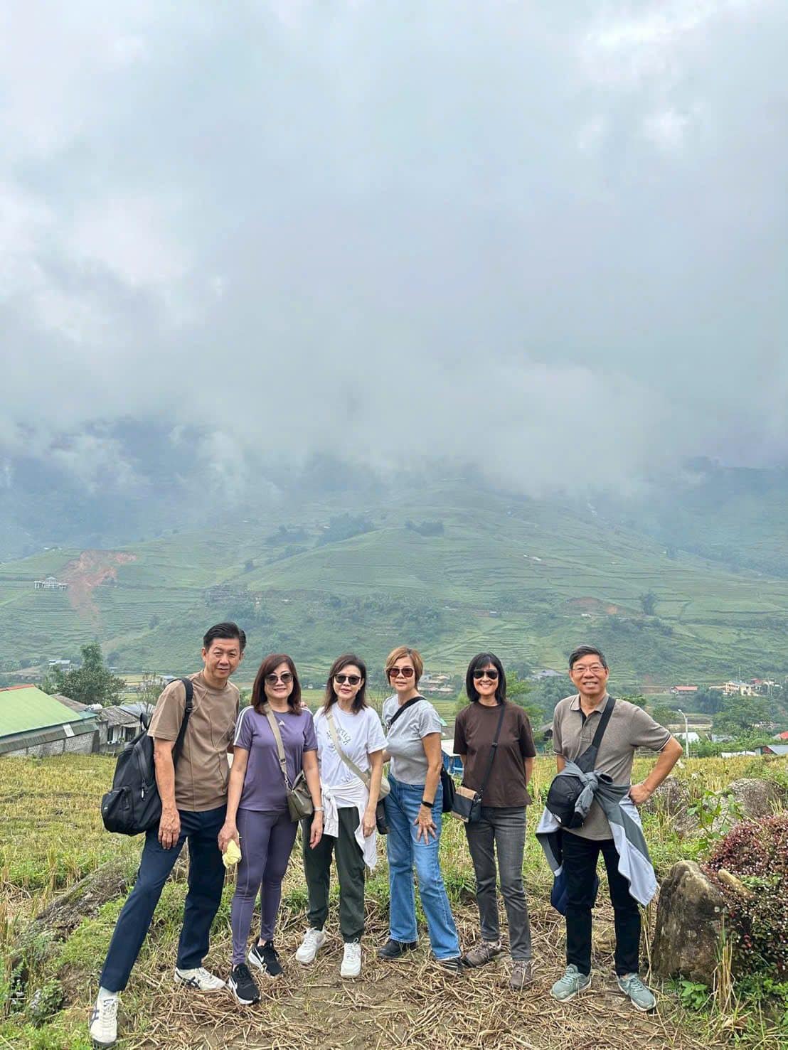 A group on a green hillside with the valley clouding over behind them