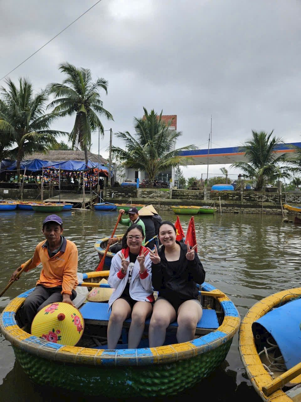 Four guests and their rower in a round bamboo basket boat on the water palm canals