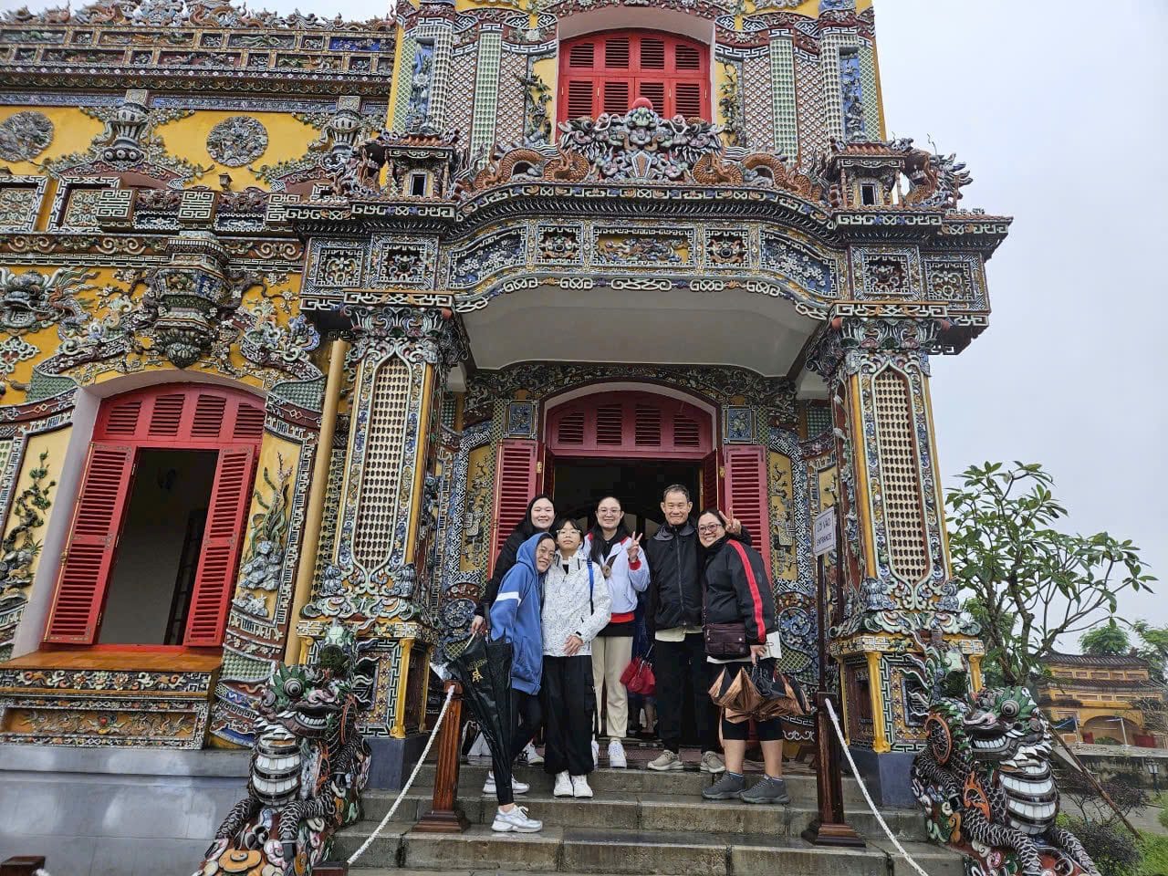 A group on the steps of a shrine facade covered in porcelain mosaic, with guardian dragons on the balustrade