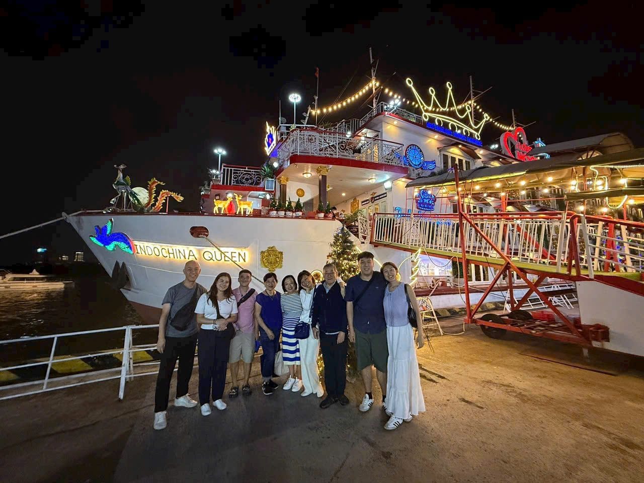 A group in front of the lit dinner boat on the Saigon River at night