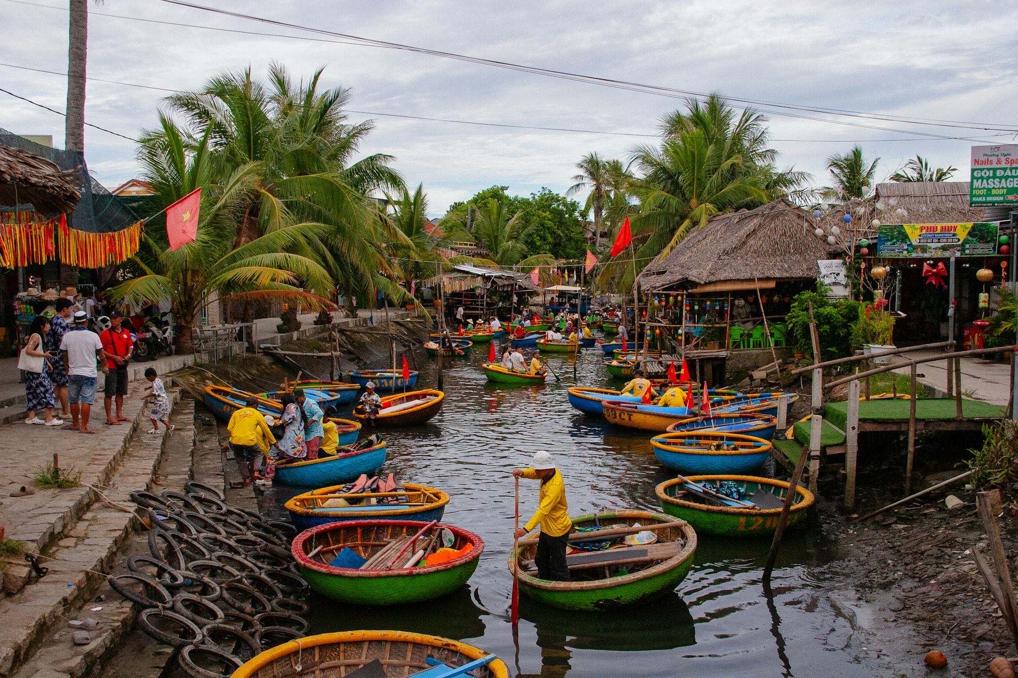 Colourful round basket boats crowding a palm-lined canal in the coconut village near Hoi An