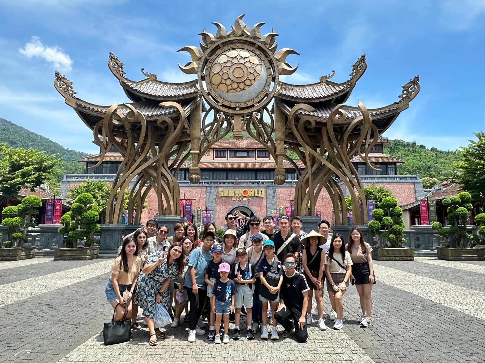 A tour group gathered under the golden sun gate at the entrance to Sun World Ba Na Hills