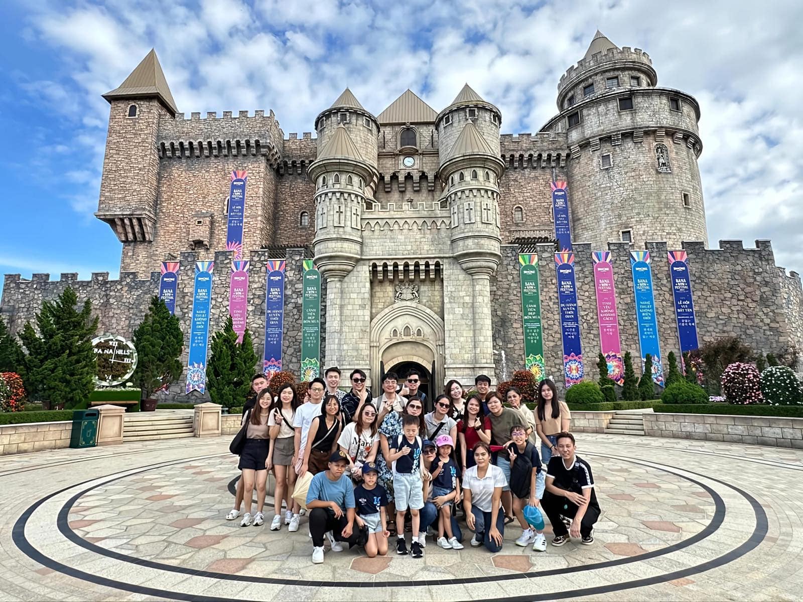 A tour group in the courtyard of the stone castle at Ba Na Hills, festival banners along its walls