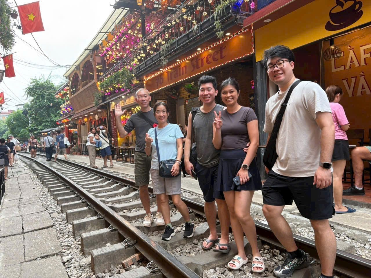 A group standing on the rails of Hanoi Train Street between the cafes