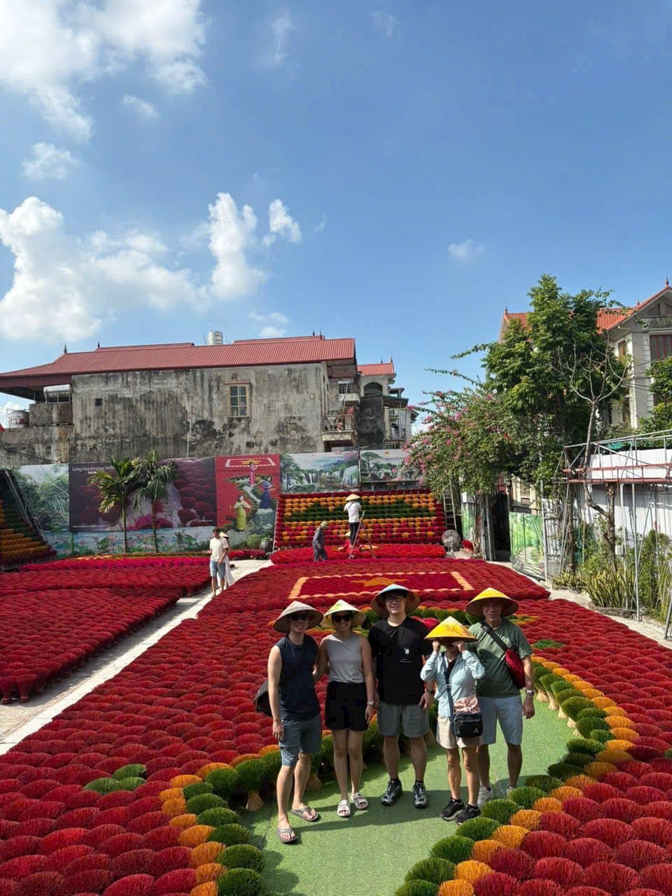 Guests in conical hats among the fanned bundles of red incense sticks